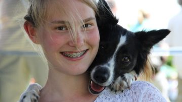 Mädchen und Hund schauen in die Kamera