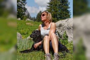 Frau entspannt mit Labrador in Natur