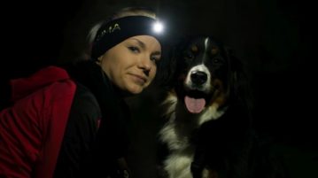 LUMA Enlite: Clevere Beleuchtungsidee für Herrchen und Hund Frau und Hund schauen in Kamera. Die Frau trägt ein Stirnband mit LED-Lampe