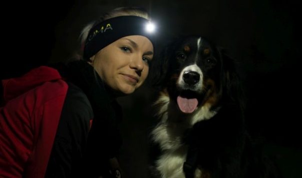 LUMA Enlite: Clevere Beleuchtungsidee für Herrchen und Hund Frau und Hund schauen in Kamera. Die Frau trägt ein Stirnband mit LED-Lampe