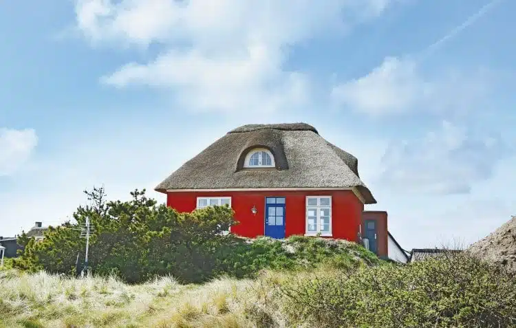 Rotes Ferienhaus mit blauer Tür und Reetdach