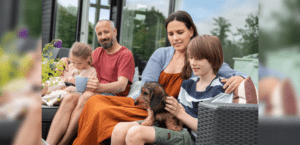 Eine Familie mit 2 Kindern und einem Dackel sitzen auf einem Outdoor-Sofa