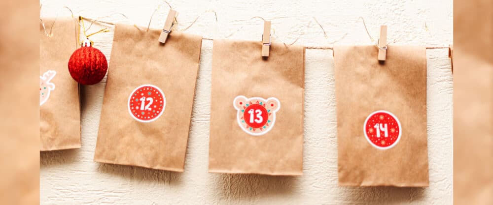 Adventskalender aus braunen Papiertüten mit Zahlen 12, 13 und 14, aufgehängt an einer Schnur.