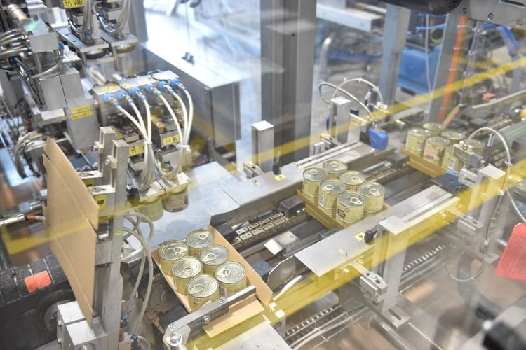 Mehrere Dosen Tierfutter werden in einer automatisierten Verpackungsmaschine für den Versand vorbereitet.
