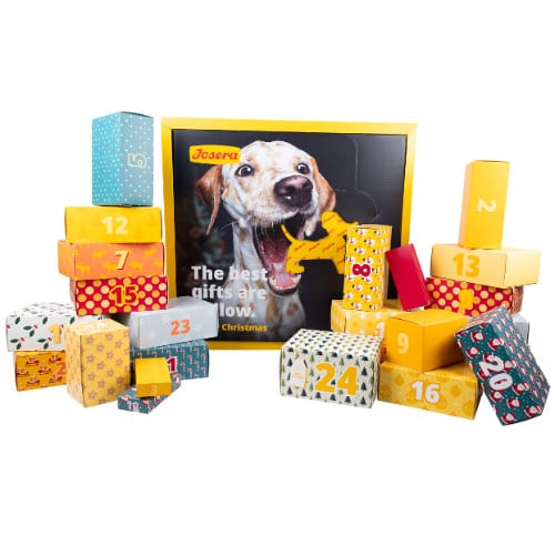 Bunter Josera Adventskalender für Hunde, umgeben von hübsch gestalteten Geschenkboxen mit Zahlen für die Weihnachtszeit.