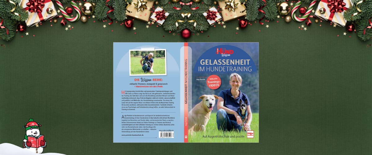 Buchcover „Gelassenheit im Hundetraining“ vor weihnachtlicher Dekoration, Anja Petrick sitzt mit 2 Hunden auf einer Wiese.