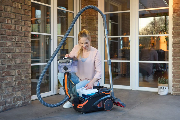 Frau mit THOMAS PET & FAMILY PRO 4ALL Sauger und Filterboxen vor Wohnhaus.