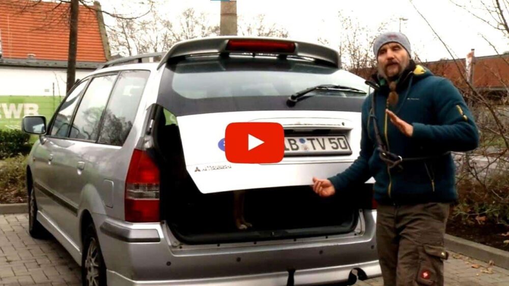 Holger Schüler steht am halb geöffneten Kofferaum eines Autos und erklärt etwas.